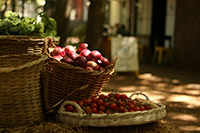 A few wicker baskets outside in a farmer's market setting with bright red fruits inside