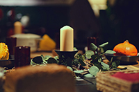 A table setting with a candle in the middle of the table with green leaves surrounding the candle